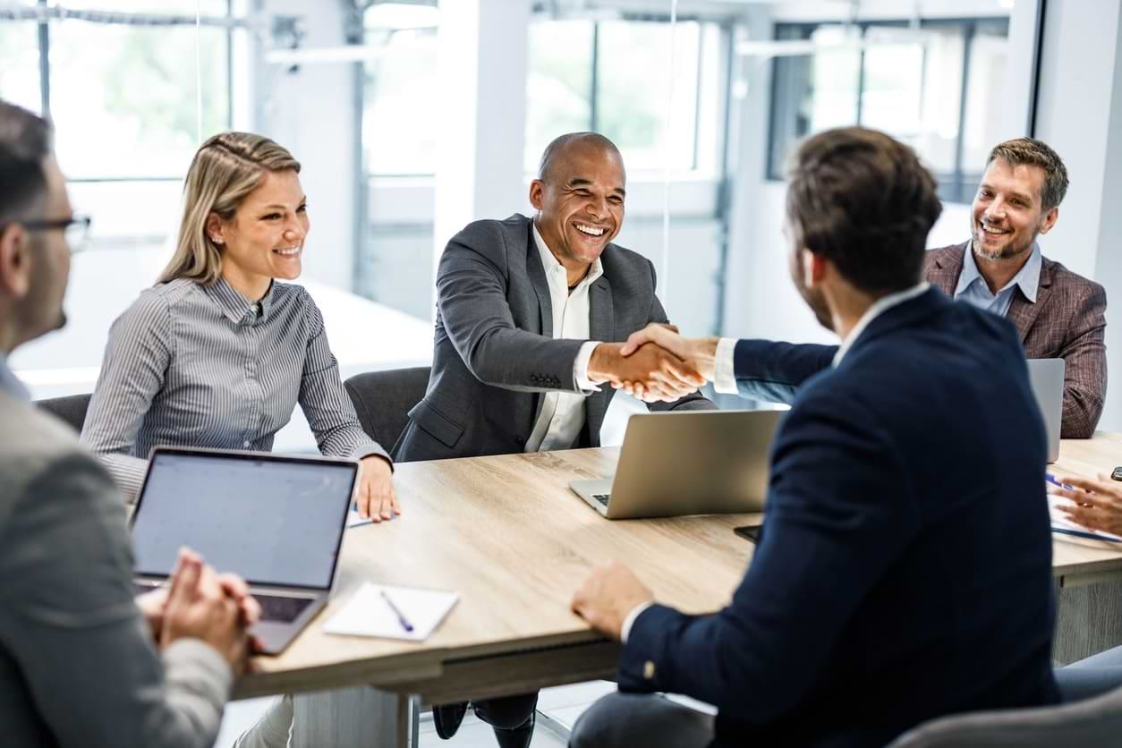 Business professionals shaking hands in a meeting, symbolizing collaboration at PEO Canada